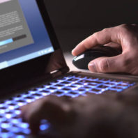 Man installing software in laptop in dark at night. Hacker loading illegal program or guy downloading files. Cyber security, piracy or virus concept.